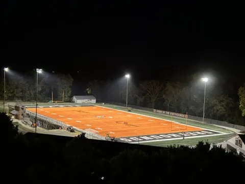 The orange turf field lit up at night for a Friday game